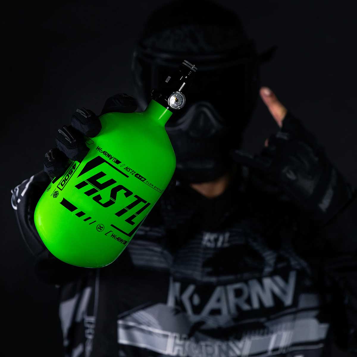 Player in HK Army clothing and goggle holding the neon green HK Army HSTL 68ci 4500psi Carbon Fiber Air Tank