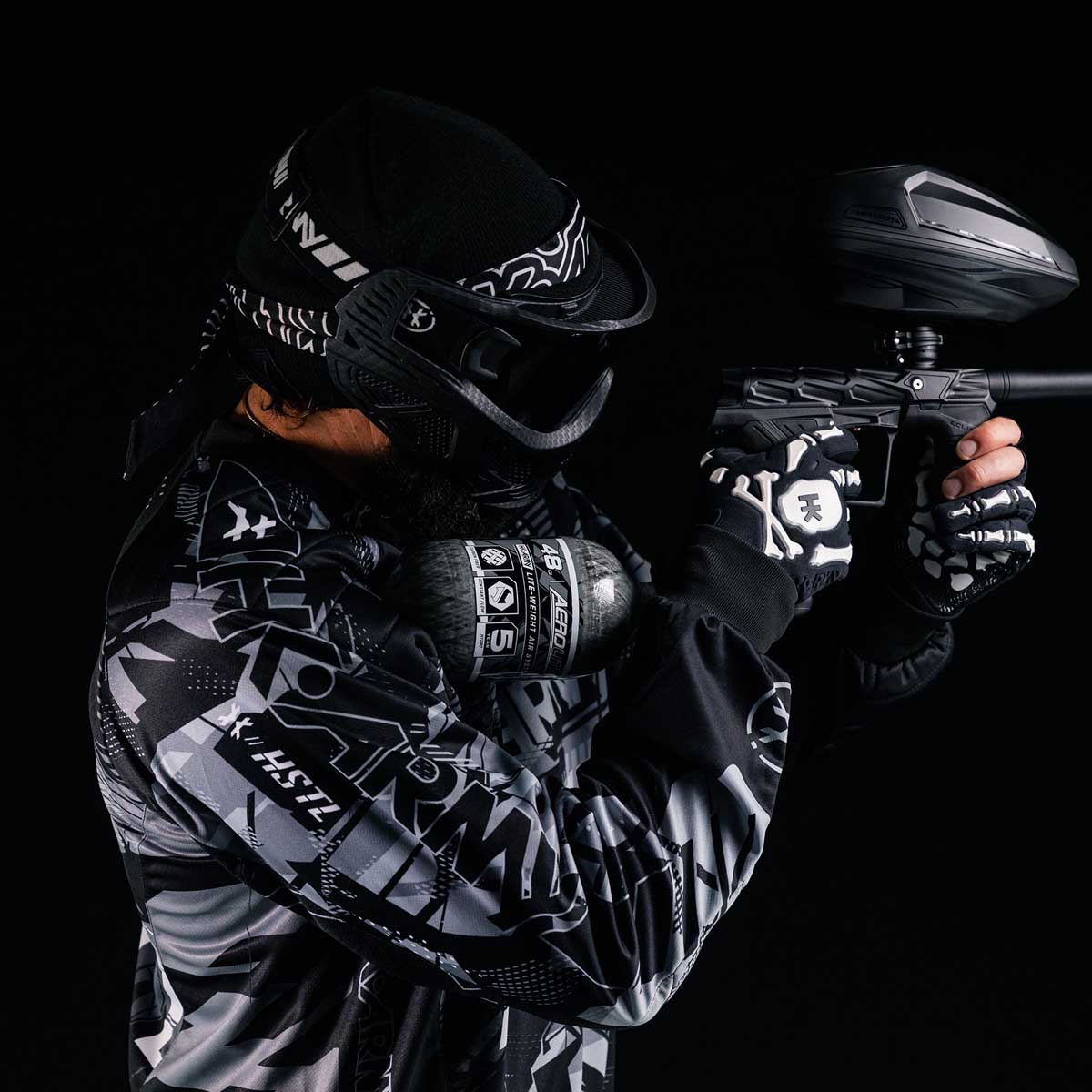 Player shooting a paintball marker with a HK Army Aerolite 48ci 4500psi Compressed Air Tank Clear attached.