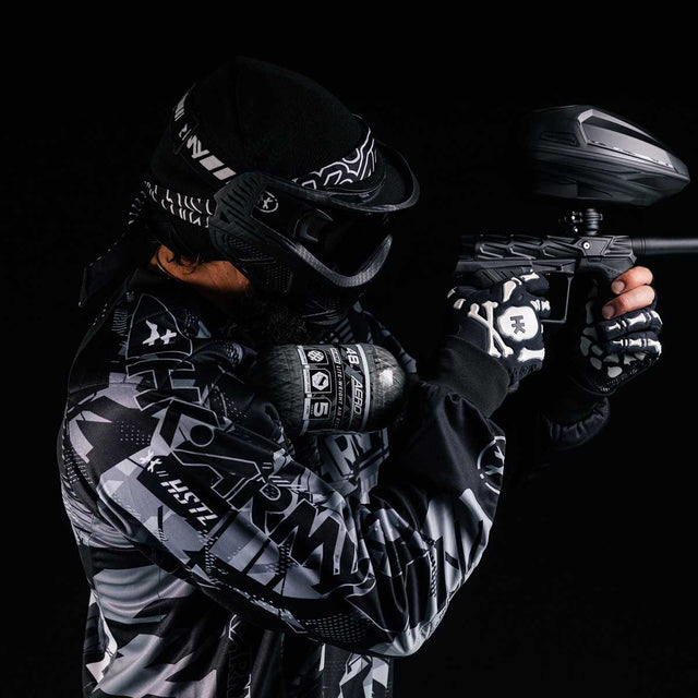 Player shooting a paintball marker with a HK Army Aerolite 48ci 4500psi Compressed Air Tank Clear attached.