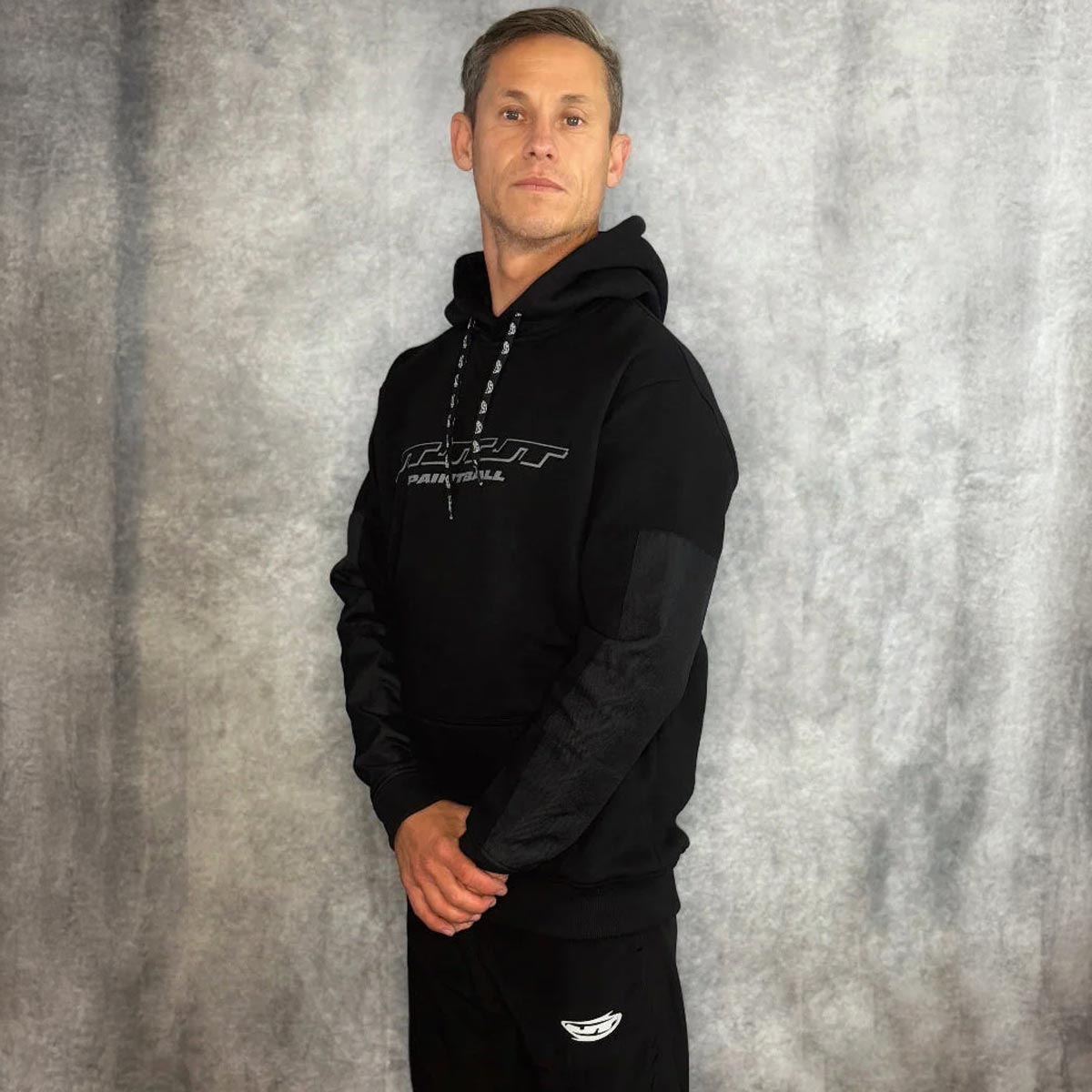 JT Paintball Grind Playing Hoodie Black on a person on a grey background