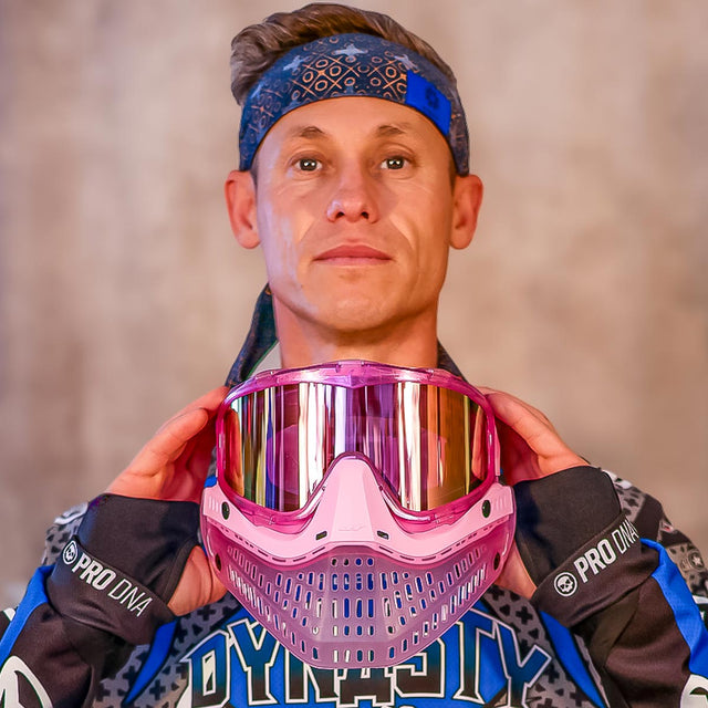 Person holding a pink JT Paintball mask with a blurred background