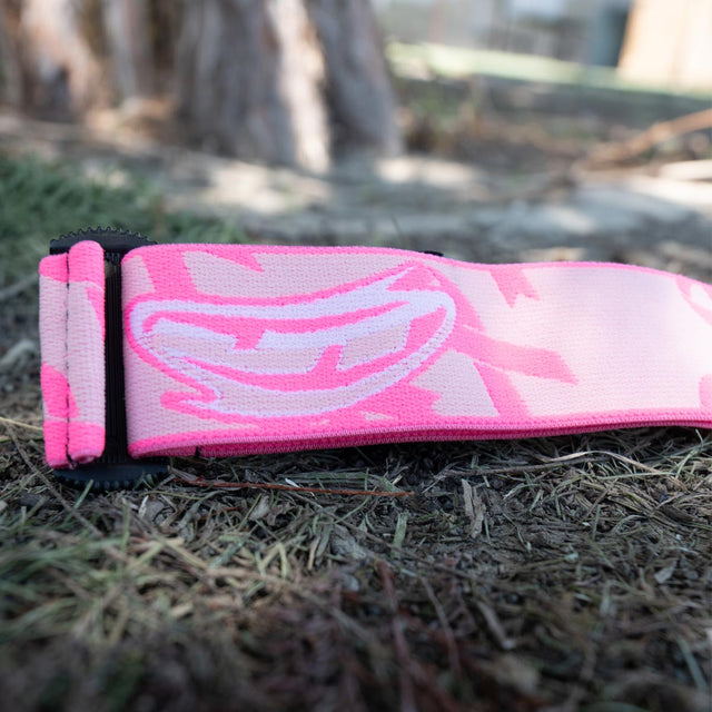 Pink and black camouflage-patterned JT goggle strap on grass
