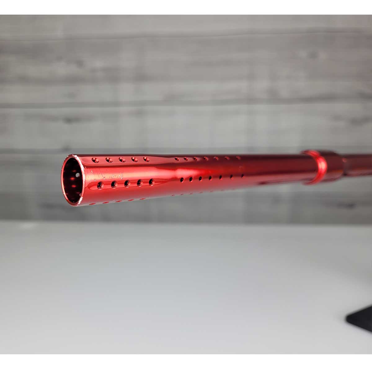 Left side close up of barrel front USED Red and black with white splash pattern Dye M3+ Paintball Marker Red Splash on a woodgrain background.