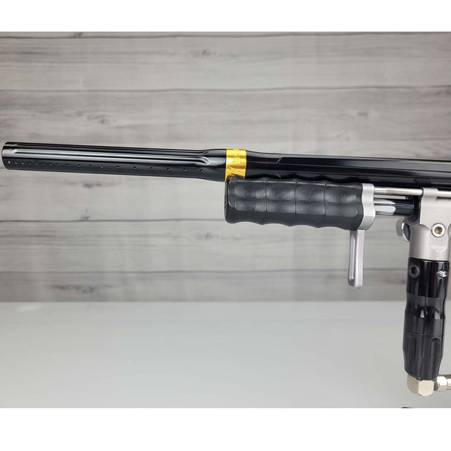 Left side barrel USED Empire Sniper Pump Grey paintball marker with a black and silver design on a white surface with a wooden background
