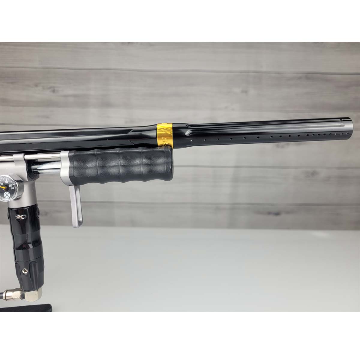 Right side barrel USED Empire Sniper Pump Grey paintball marker with a black and silver design on a white surface with a wooden background