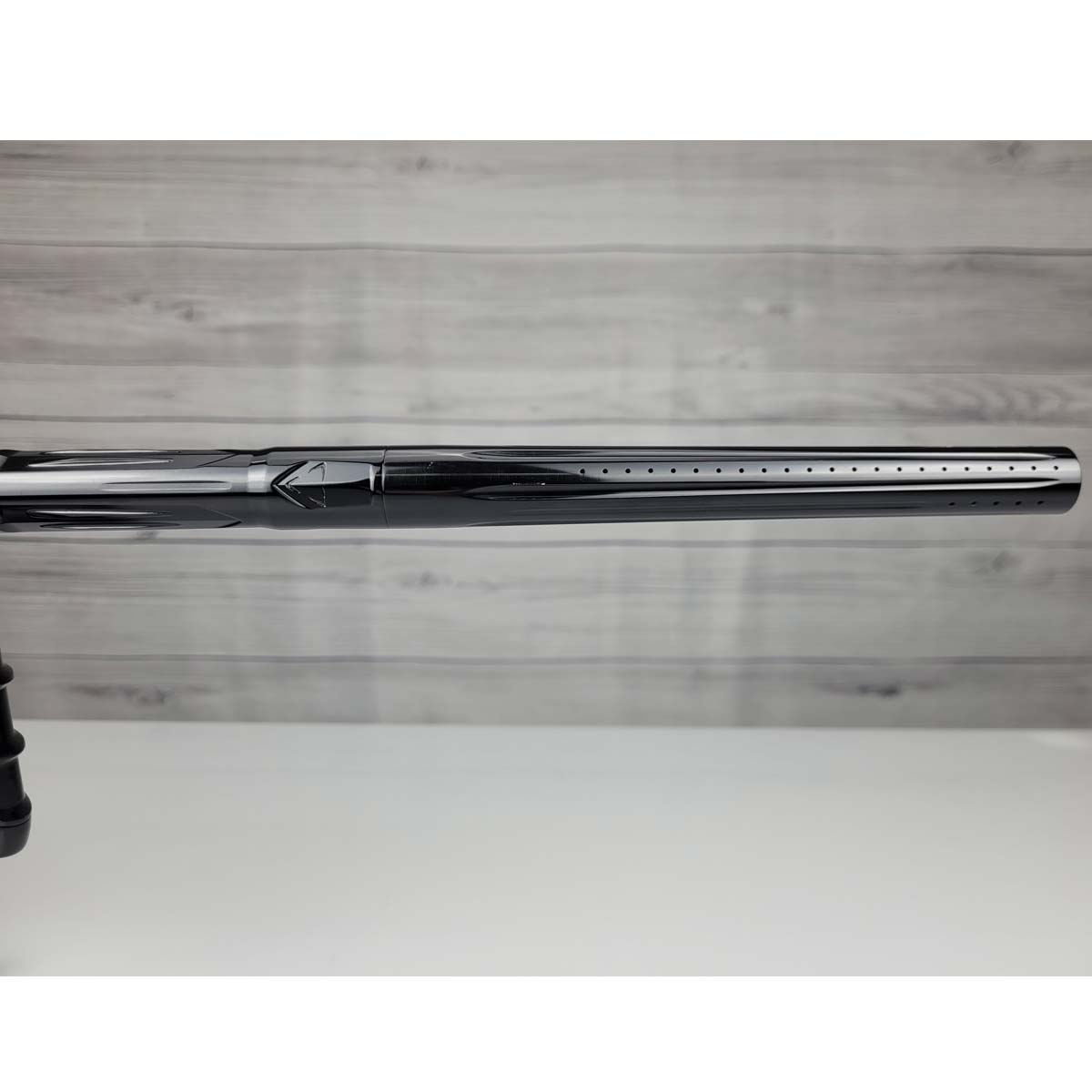 Right side barrel close up USED DLX Luxe IDOL Paintball Marker Black Polished on a woodgrain background