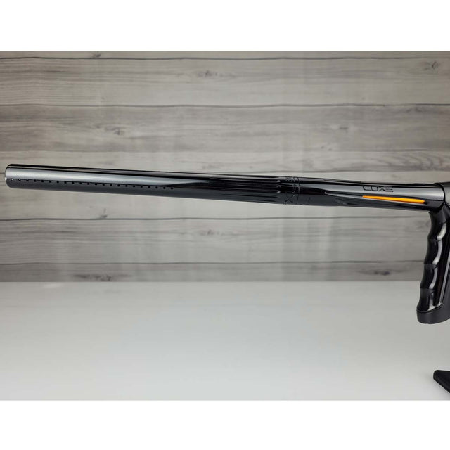 Left side barrel USED DLX Luxe TM40 Paintball Marker Black against a woodgrain background