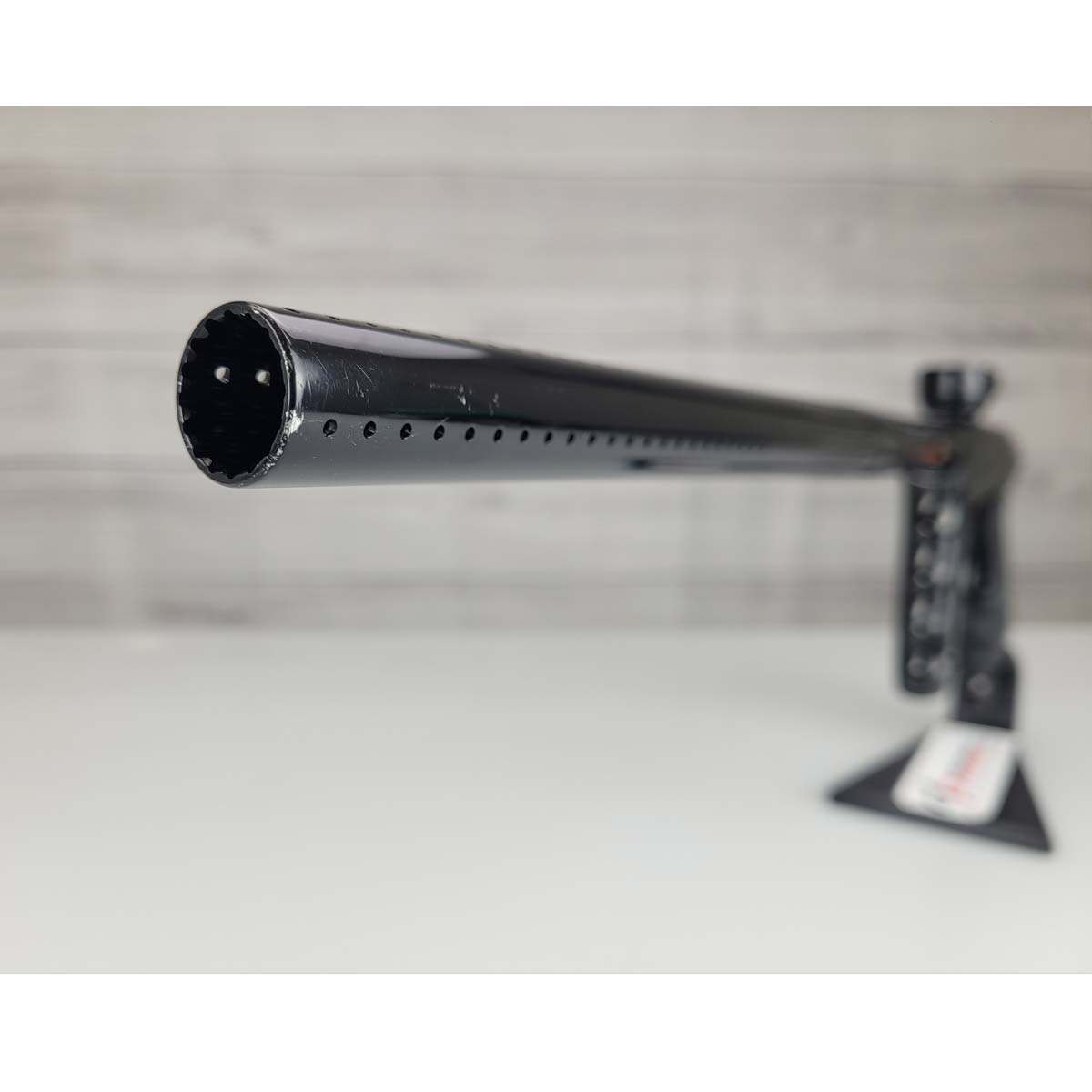 Barrel tip close up USED DLX Luxe TM40 Paintball Marker Black against a woodgrain background