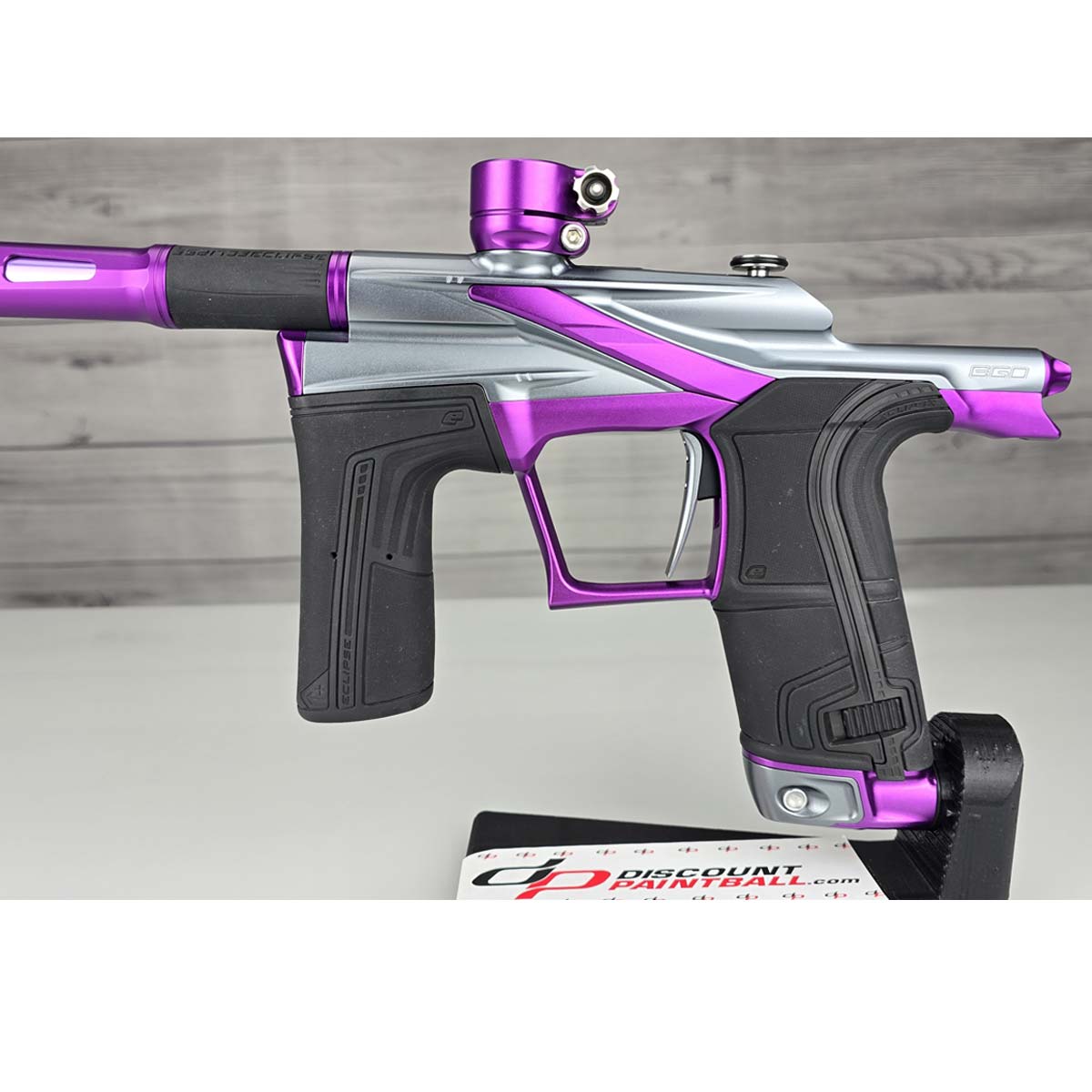 Close up of left side body Purple and silver USED Planet Eclipse LV2 Paintball Marker Havoc Grey Purple on a white surface with a wooden background