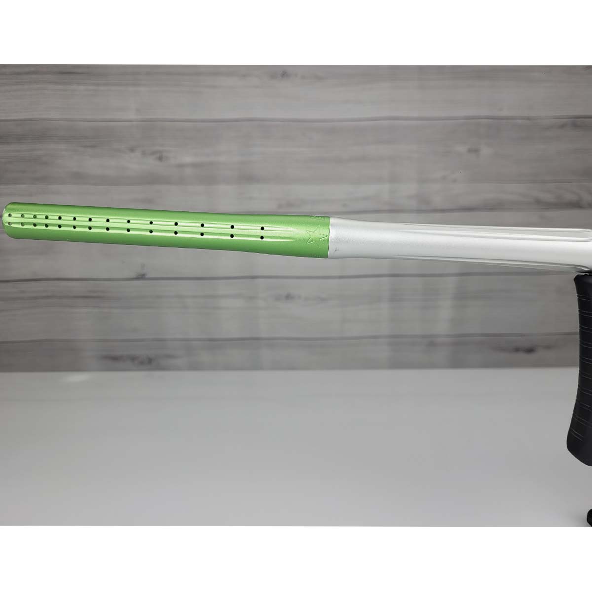 Left side barrel close up Green and silver USED Planet Eclipse Geo 3.5 Kyrpton Ice Green Silver paintball marker on a wood panel background.