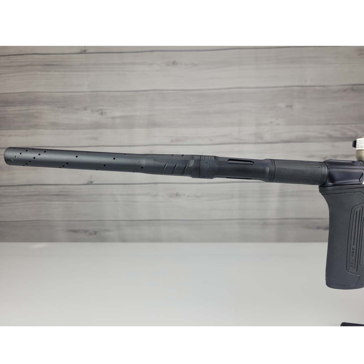 Left side barrel USED Planet Eclipse CS2 Paintball Marker Black Sandstone on a white surface and wooden background