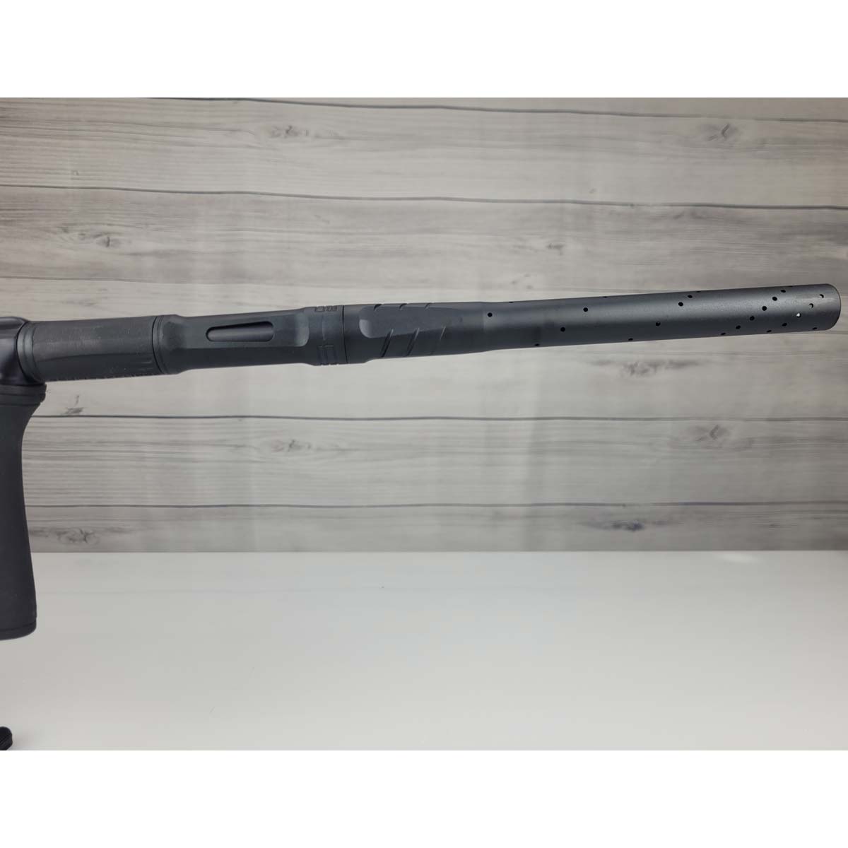 Right side barrel USED Planet Eclipse CS2 Paintball Marker Black Sandstone on a white surface and wooden background