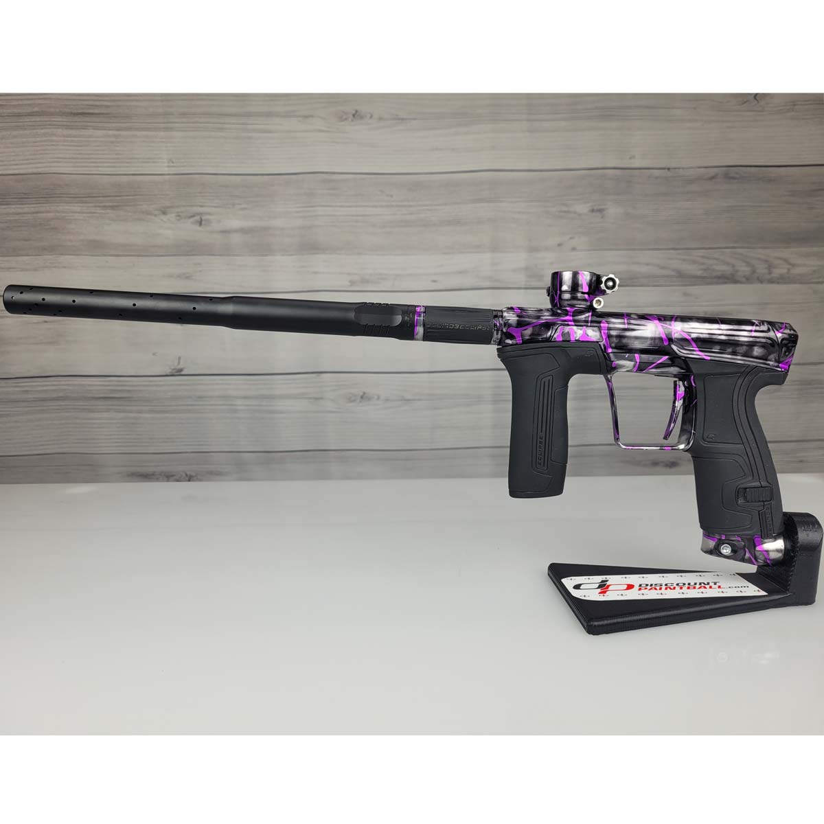 Left side USED Planet Eclipse CS2 Paintball Marker Black Purple Grey Splash in a marker stand on a woodgrain background