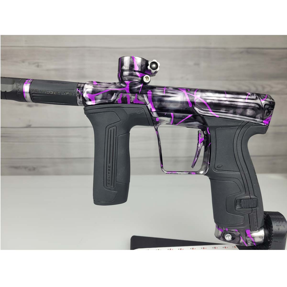 Left side body USED Planet Eclipse CS2 Paintball Marker Black Purple Grey Splash on a woodgrain background