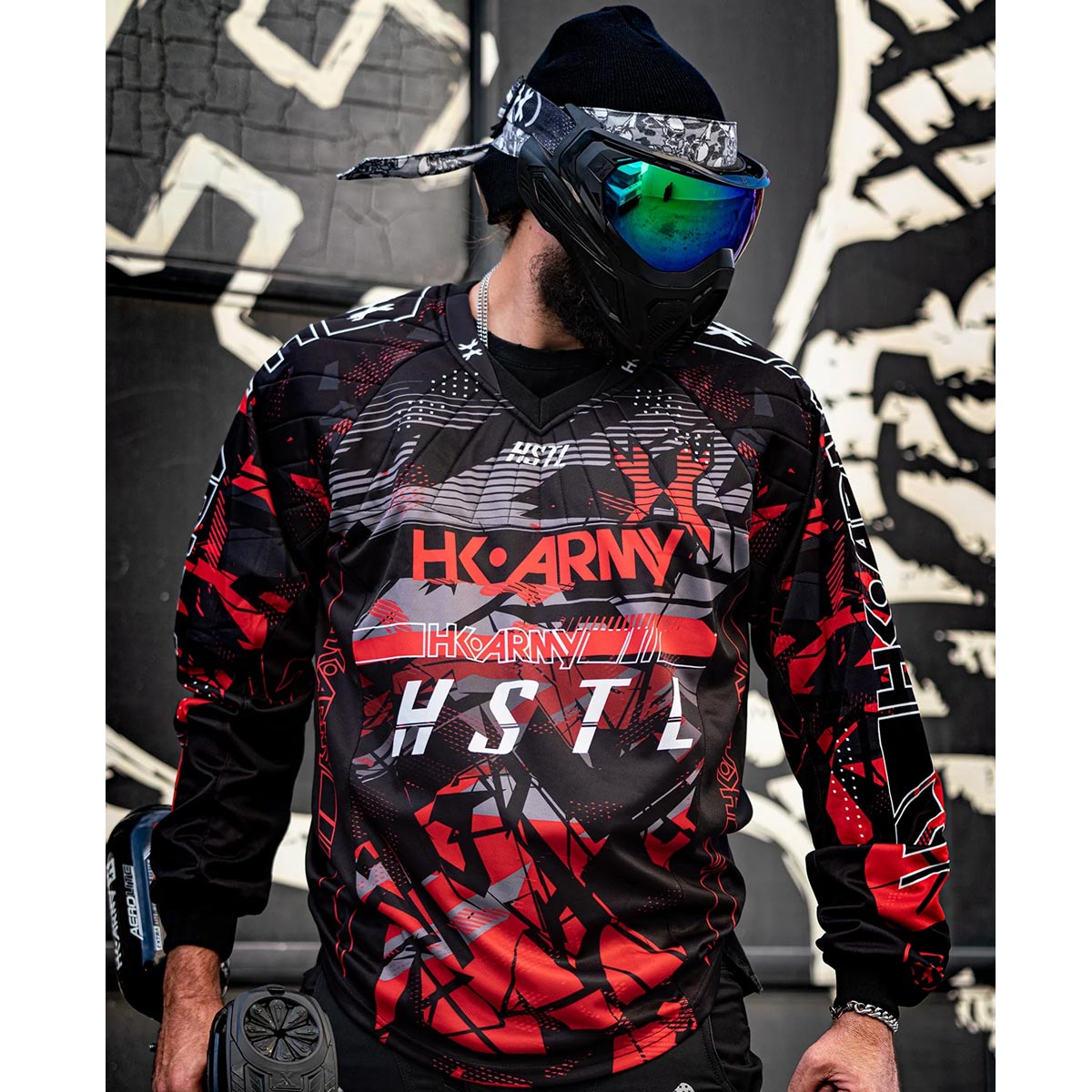 Red, black, white and grey HK Army HSTL Lava long sleeve Jersey on a person dressed for paintball on a busy background