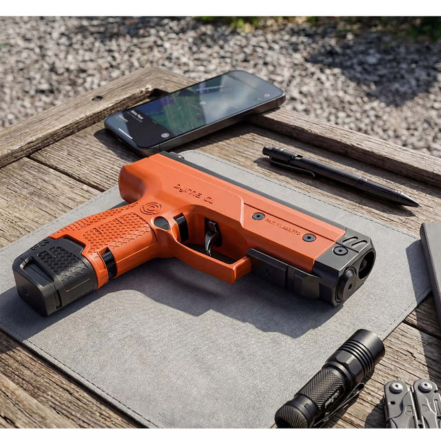 Byrna CL-XL orange left side view with 7 round magazine and 12 gram co2 on a wood table