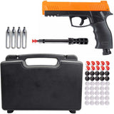 The image shows a .50 caliber Umarex HDP50 Gen 2 P2P Home Defense Pistol with orange accents, accompanied by 12-gram CO2 cartridges, a cleaning rod, a lockable case, and a assortment of round projectiles included pepper rounds.