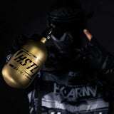 A player in HK Army clothing holding a HK Army HSTL 68ci 4500psi Carbon Fiber Air Tank Gold Black in one hand