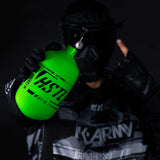 Player in HK Army clothing and goggle holding the neon green HK Army HSTL 68ci 4500psi Carbon Fiber Air Tank