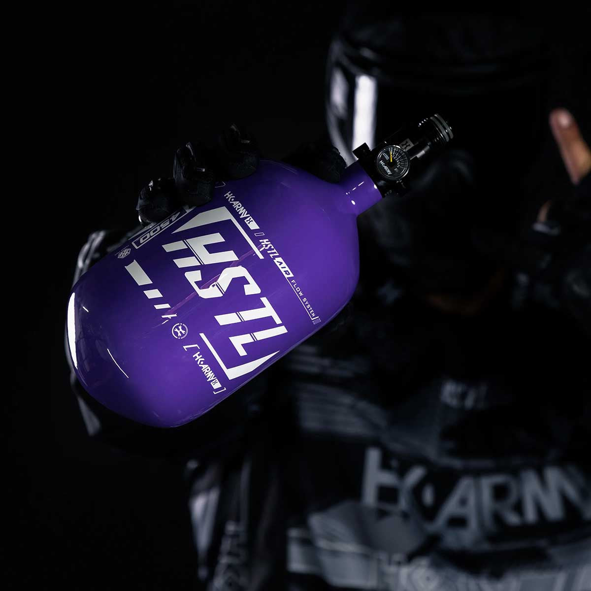 Paintball Player holding the HK Army HSTL 68ci 4500psi air tank in purple and white