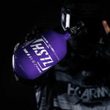 Paintball Player holding the HK Army HSTL 68ci 4500psi air tank in purple and white