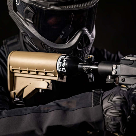Close up of a person with a A black aluminum HK Army 9ci 3000 PSI high pressure tank with a black regulator shown in a stock.