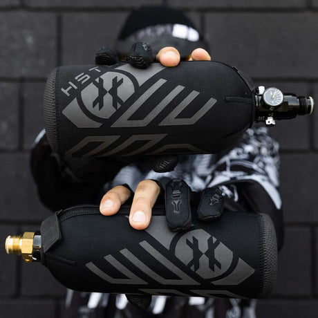 HK Army HSTL 48ci 20oz Tank Cover on a 3000 psi tank and a 20 oz CO2 tank being held by a person
