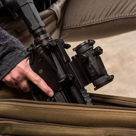 Right side view black AXEON 7XRGB20 Optic Tri Color Dot Sight mounted on a rifle being held by a person.