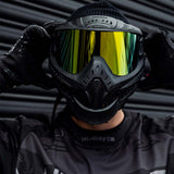 Front of Black HK Army HSTL Thermal Paintball Goggle mask with a gold lens and white AH logo on the side shown on a person. 