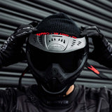 Black HK Army HSTL Thermal Paintball Goggle mask with a smoke lens and white AH logo on the side, shown on a person adjusting the goggle.