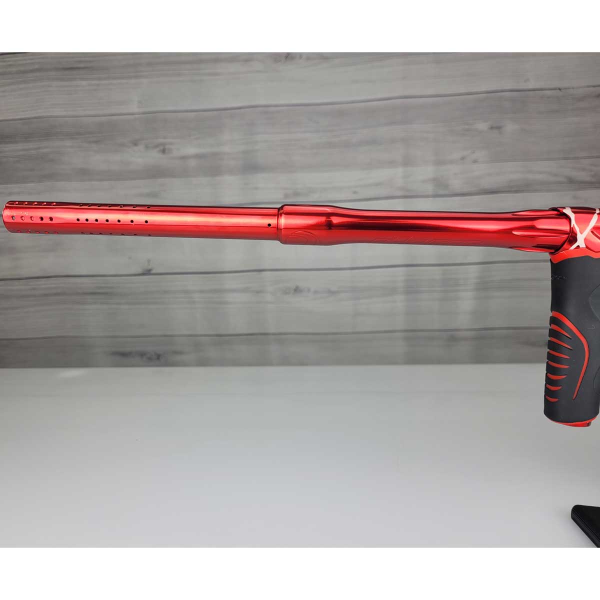 Left side barrel USED Red and black with white splash pattern Dye M3+ Paintball Marker Red Splash on a woodgrain background.