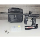 Left side USED Empire Axe 2.0 Paintball Marker Black  with case and tools on a woodgrain background
