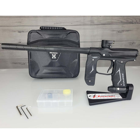 Left side USED Empire Axe 2.0 Paintball Marker Black  with case and tools on a woodgrain background