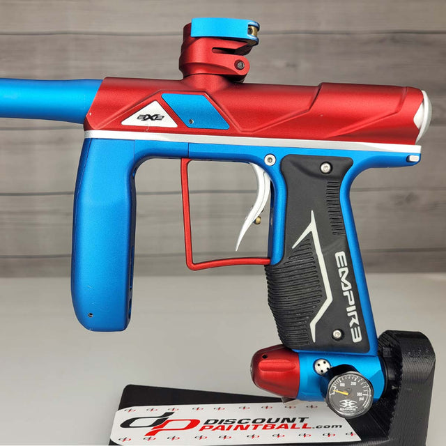 Left side body USED Empire Axe Pro Red Blue Silver paintball marker on a panel background.