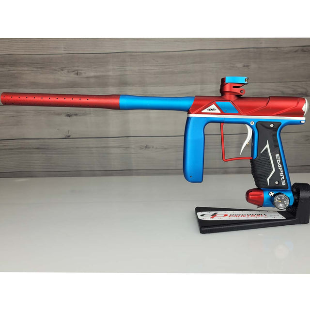 Left side USED Empire Axe Pro Red Blue Silver paintball marker on a panel background.