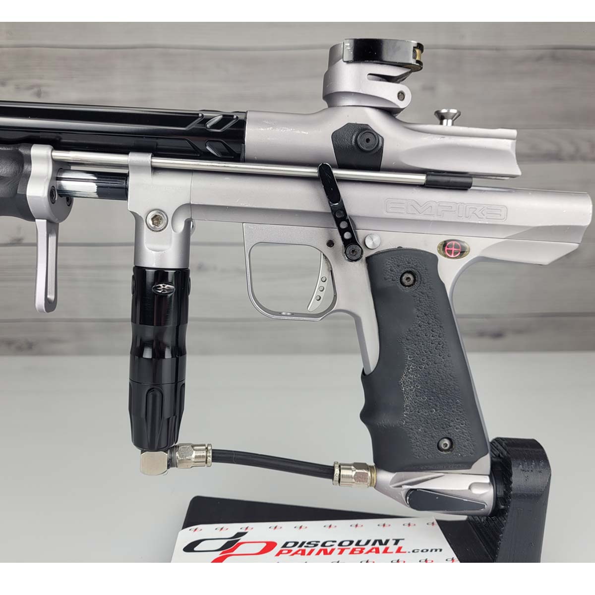 Left side body USED Empire Sniper Pump Grey paintball marker with a black and silver design on a white surface with a wooden background