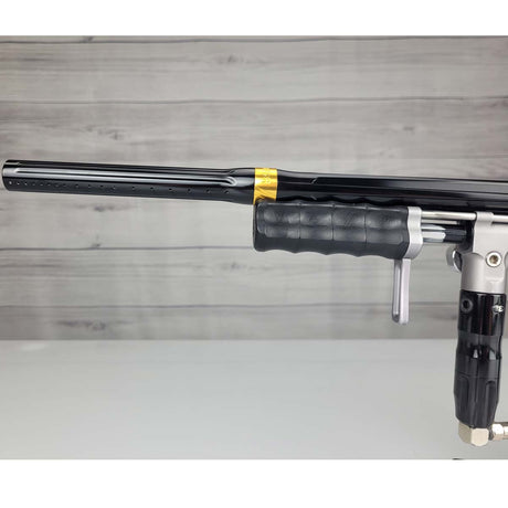 Left side barrel USED Empire Sniper Pump Grey paintball marker with a black and silver design on a white surface with a wooden background