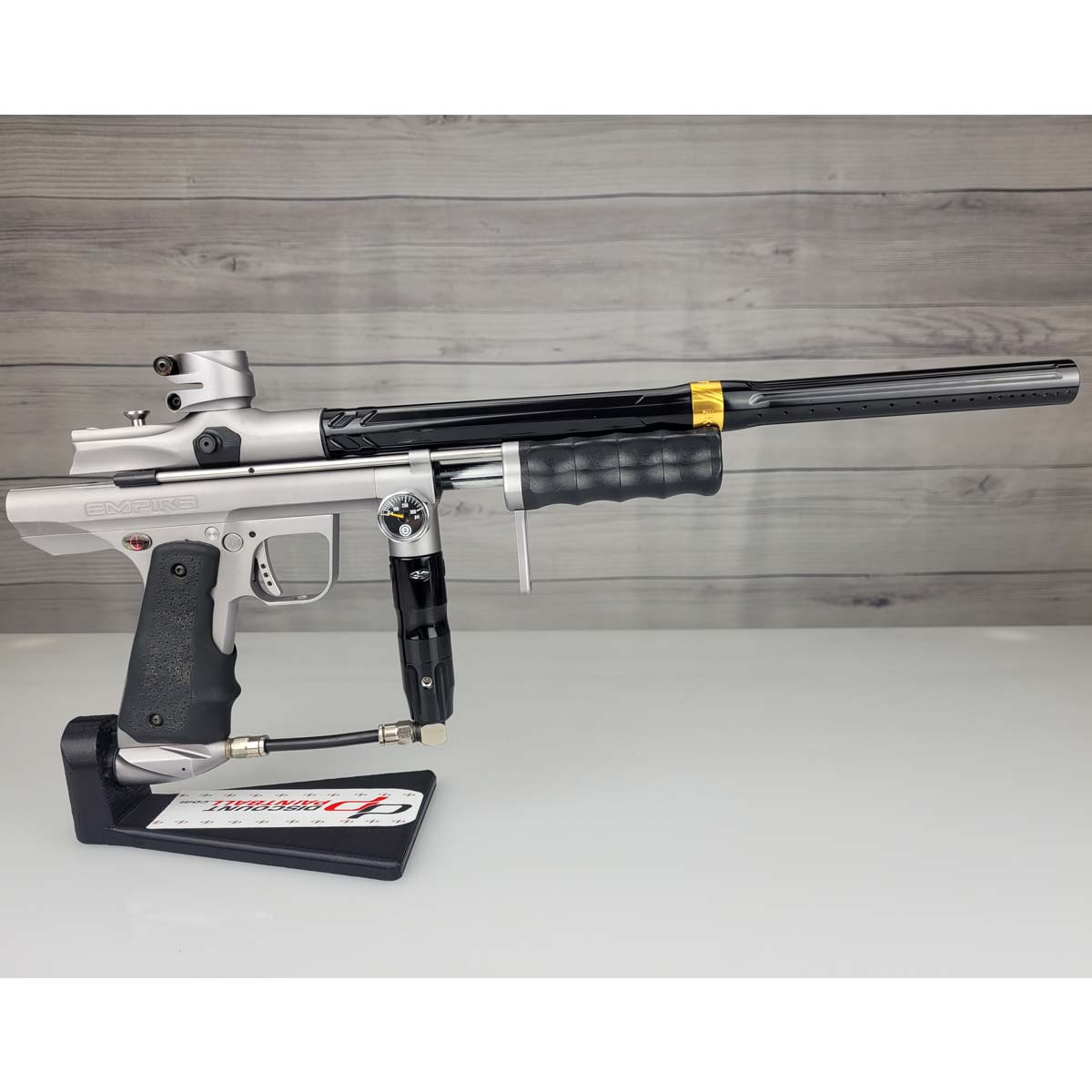 Right side USED Empire Sniper Pump Grey paintball marker with a black and silver design on a white surface with a wooden background