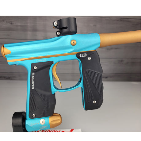 Blue and black paintball gun with gold accents on a wooden background