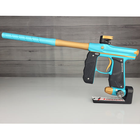 Blue and gold paintball gun on a gray surface with a wooden background