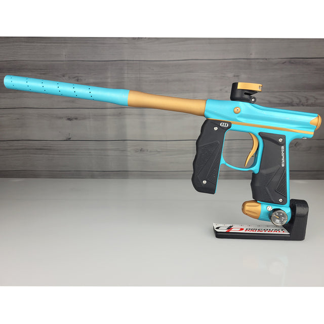Blue and gold paintball gun on a gray surface with a wooden background