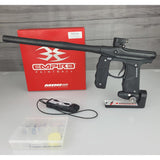 Black Empire Mini paintball gun with accessories on a gray surface, featuring Empire Paintball branding.