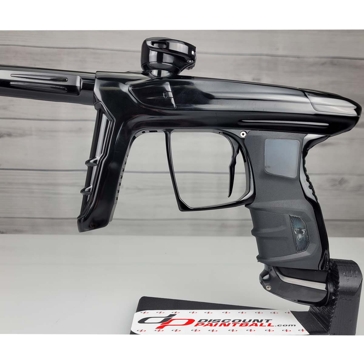 Left side close up USED DLX Luxe IDOL Paintball Marker Black Polished on a woodgrain background
