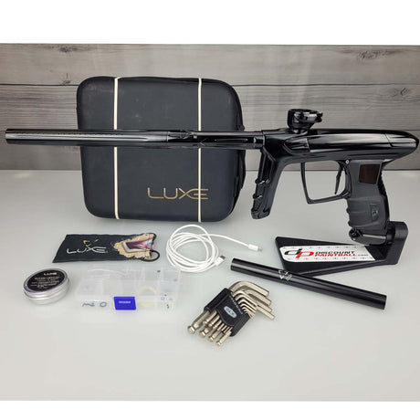 USED DLX Luxe IDOL Paintball Marker Black Polished with case and accessories on a woodgrain background