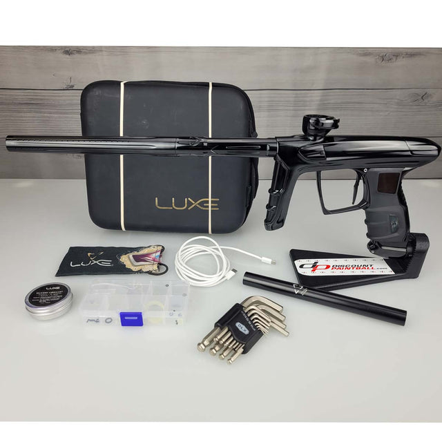 USED DLX Luxe IDOL Paintball Marker Black Polished with case and accessories on a woodgrain background