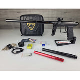 USED DLX Luxe TM40 Paintball Marker Black with case, parts and inserts against a woodgrain background