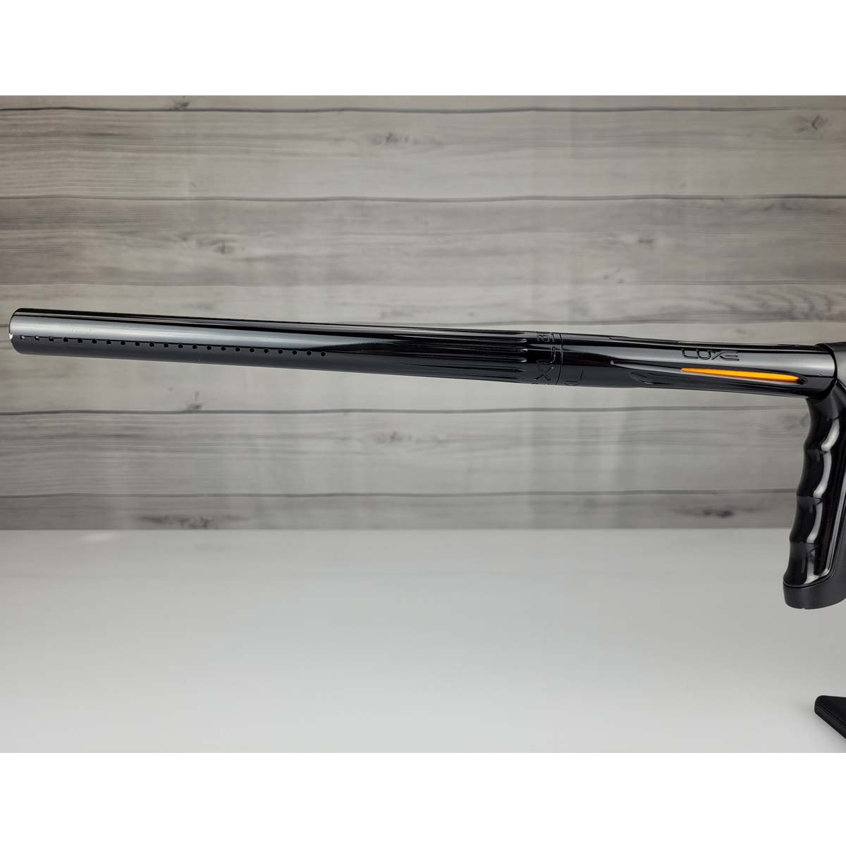 Left side barrel USED DLX Luxe TM40 Paintball Marker Black against a woodgrain background
