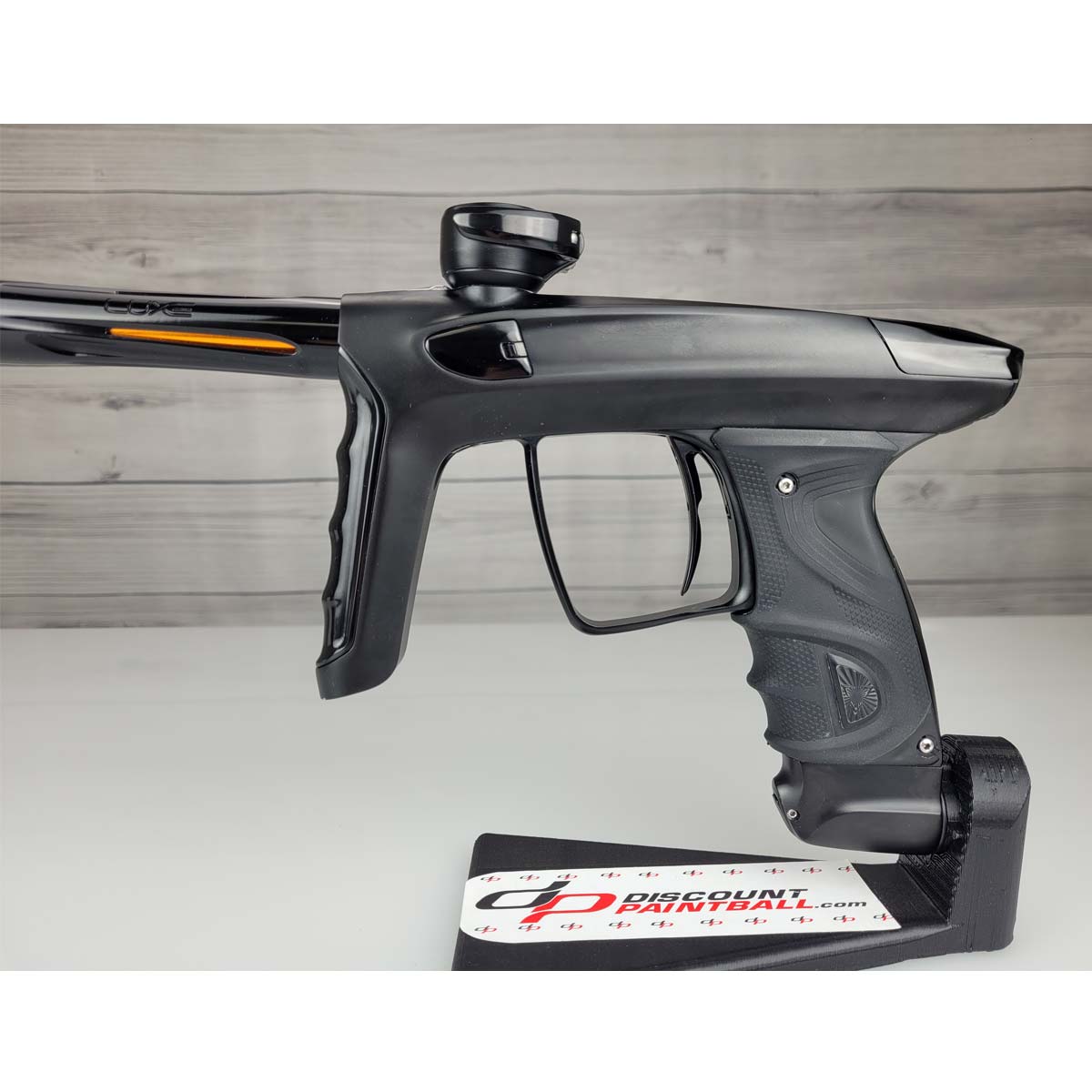 Left side body close up Left side USED DLX Luxe TM40 Paintball Marker Black against a woodgrain background