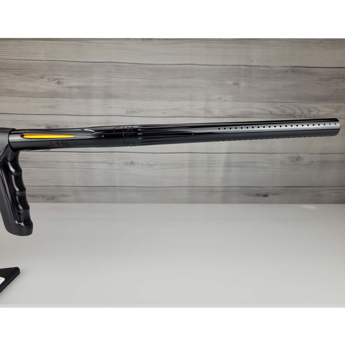 Right side barrel USED DLX Luxe TM40 Paintball Marker Black against a woodgrain background