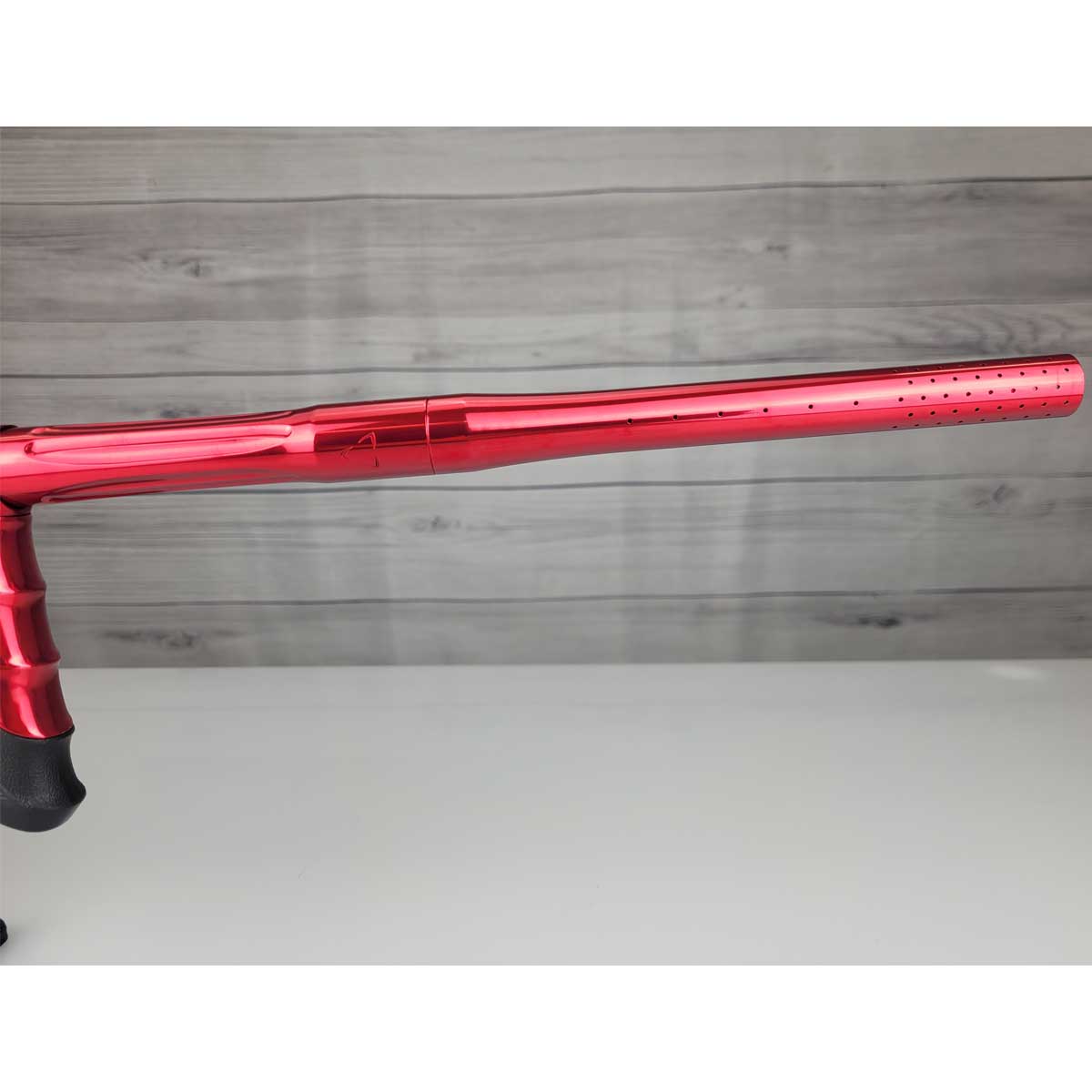 Right side barrel USED DLX Luxe Aire Red Polished paintball marker on a stand against a woodgrain background